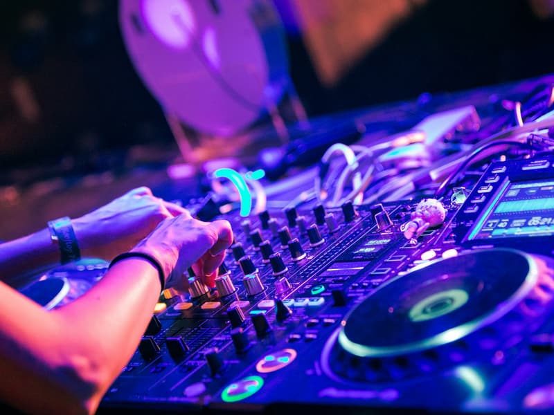 Mains d’un DJ sur un contrôleur éclairé de lumières violettes
